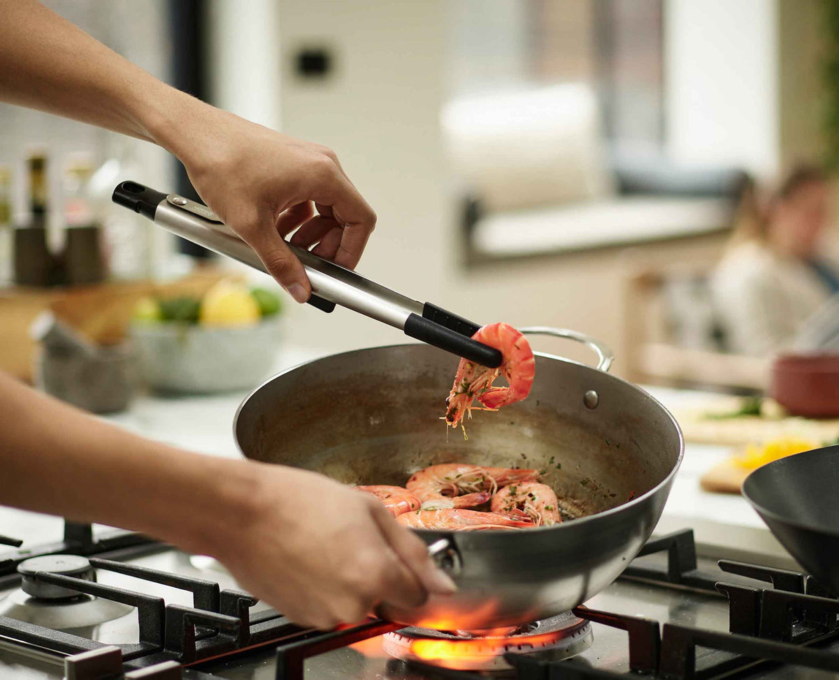 Joseph Joseph Elevate Fusion large tongs gripping food in a pan, Homelux Kenya