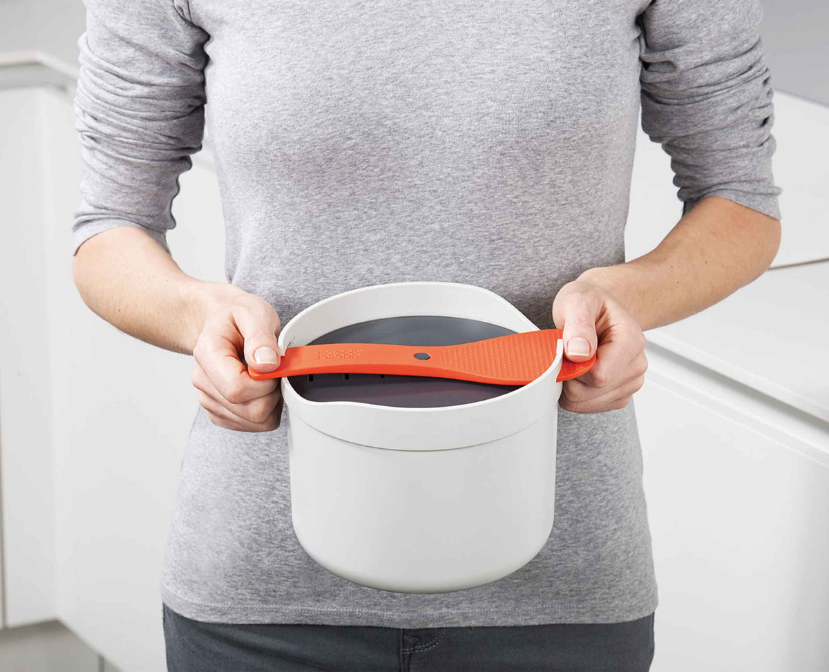 The rice cooker shown in a microwave to illustrate its size