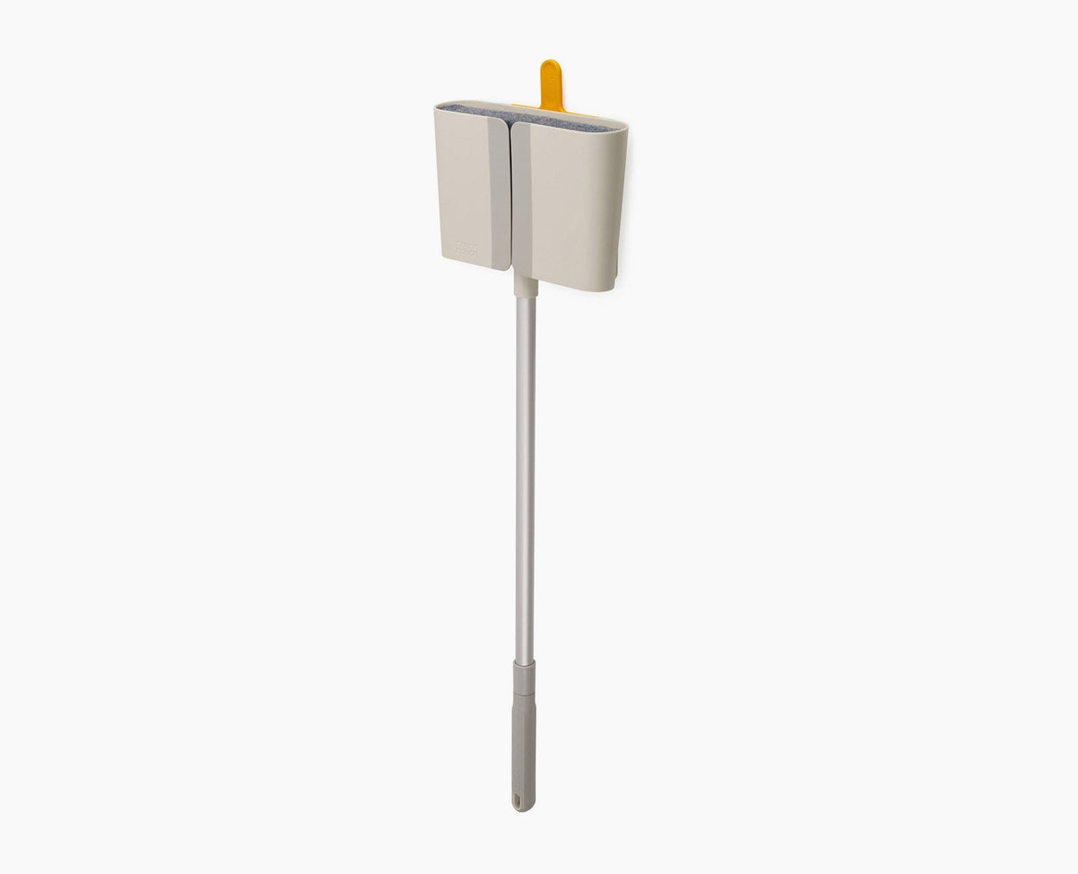Joseph Joseph CleanTech wall-mounted broom in stone, seated in its Dust-shield holder.