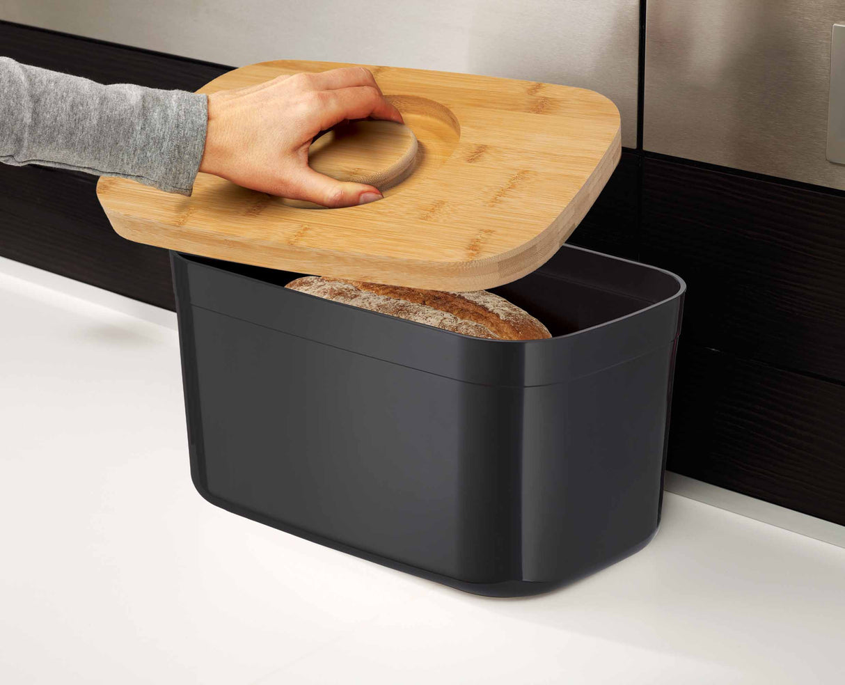 Bread being sliced on the bamboo lid used as a cutting board.