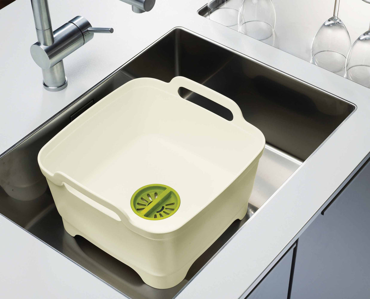 The white and green bowl lifted by its large side carry handles.