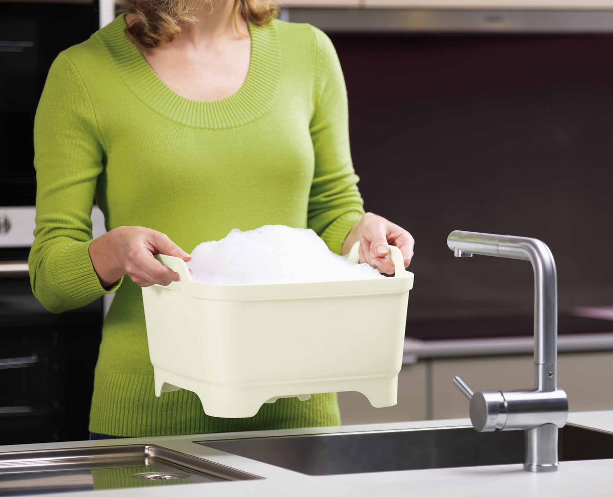 Water draining out of the washing-up bowl through the open plug.