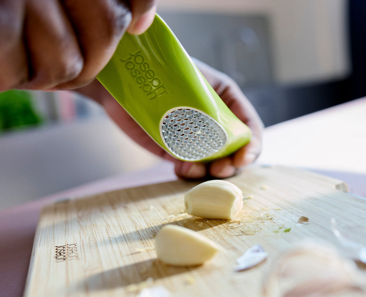 The Rocker being pressed and rocked over garlic cloves on a board.