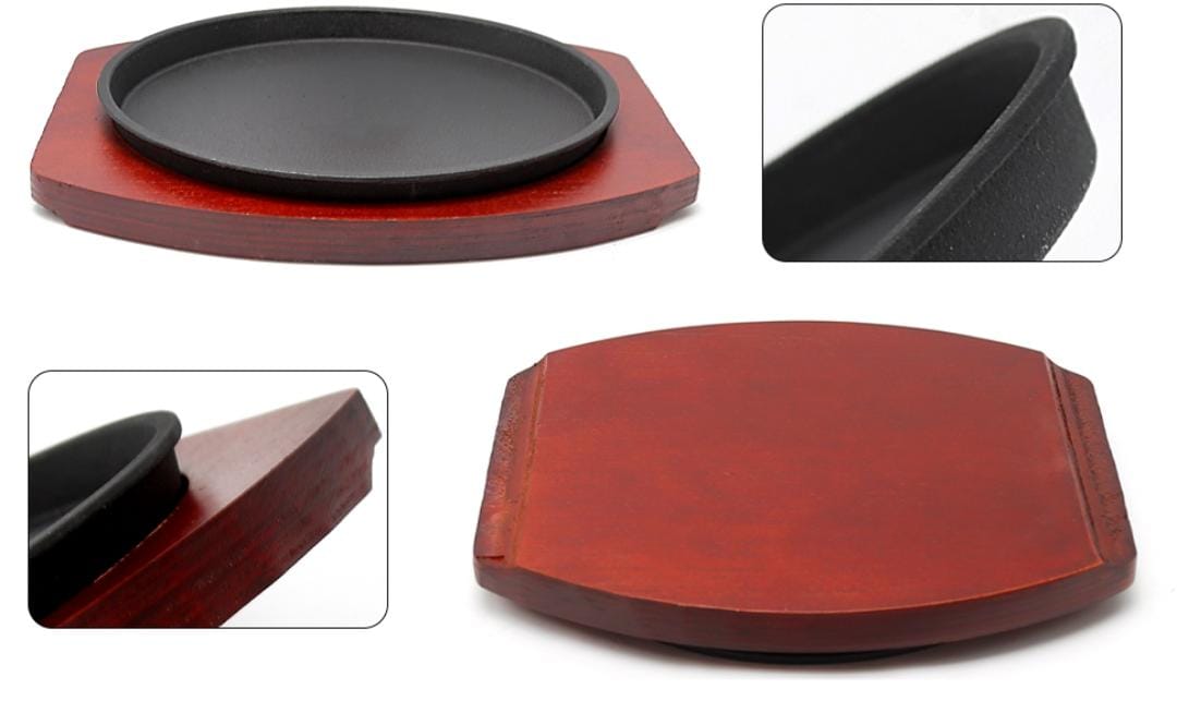 Cast iron hot sizzling plate on wooden tray