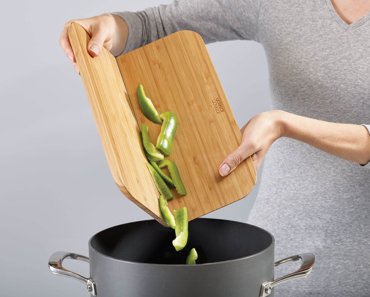 The bamboo board squeezed into its folded chute shape, tipping chopped food into a pan.