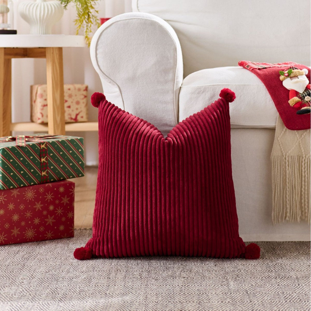 Christmas cushion cover 45x45cm, red corduroy with pom pom corners, on a white armchair
