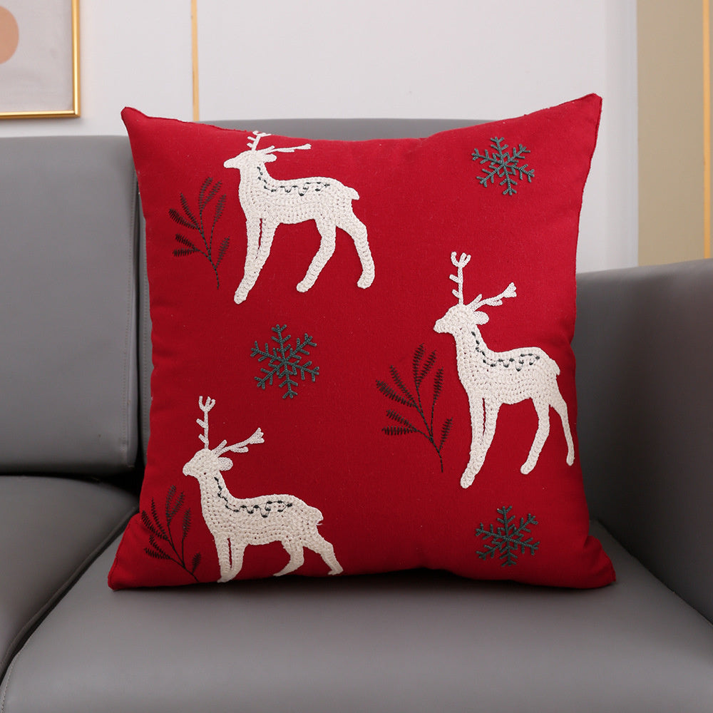 Christmas cushion cover 45x45cm, red canvas with three embroidered reindeer and snowflakes on a grey sofa