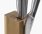 An Elevate steel knife resting on its weighted handle with the blade lifted clear of the board