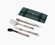 Joseph Joseph GrillOut four-piece stainless steel BBQ utensil set arranged beside its folding carry case.