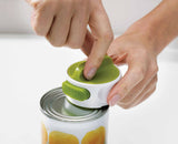 The lid-release button on the Can-Do being pressed to drop the cut lid free.