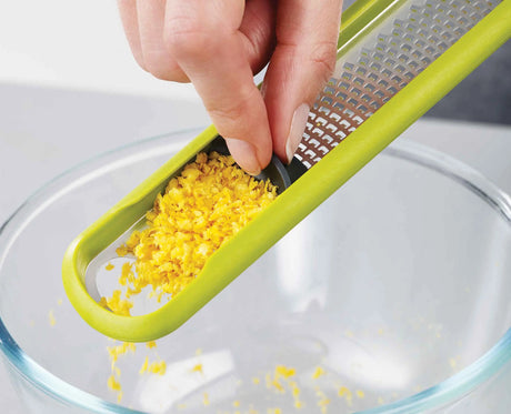 The green ergonomic handle of the Handi-Zest shown in the hand.