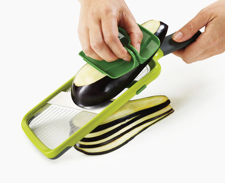 Even slices being cut with the mandoline over a bowl.