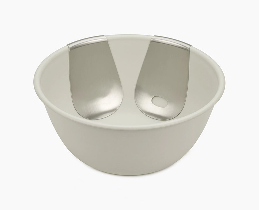Joseph Joseph Uno salad bowl in stone with both stainless-steel servers hooked onto the rim.
