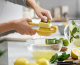 Hands squeezing the JuiceMax handles around a lemon half.
