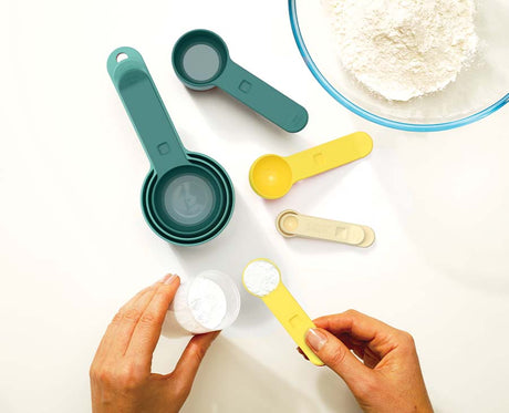 The eight opal measuring cups separated to show every size from a quarter teaspoon to one cup