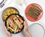 The M-Cuisine set in use cooking a meal, showing the integrated orange handles