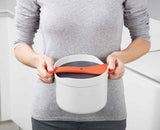 The rice cooker shown in a microwave to illustrate its size