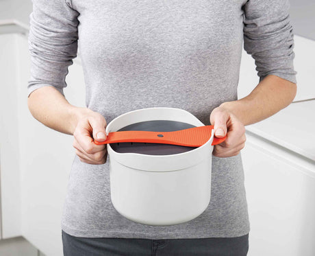 The rice cooker shown in a microwave to illustrate its size