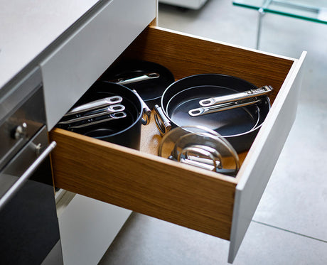 Both pans with their handles folded, stacked with the felt protector between them