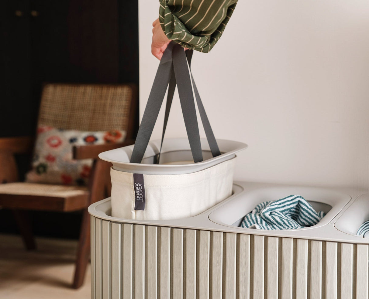 Tote bag emptied into a washing machine using the helper handle on its base.