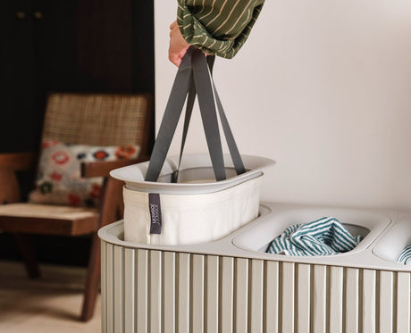 Tote bag emptied into a washing machine using the helper handle on its base.