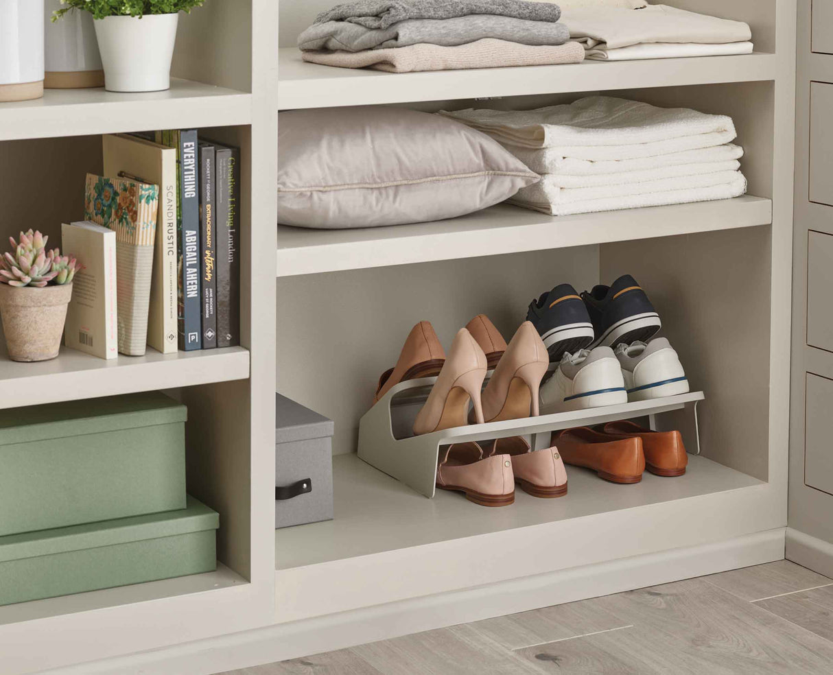 The ecru shoe rack in a hallway beside a front door.