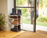 The rack holding four pairs of shoes across its adjustable shelves.