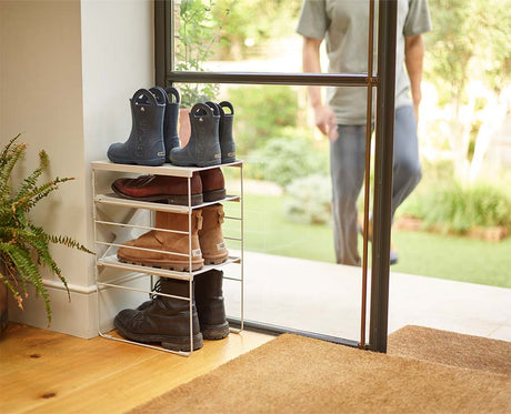 The rack holding four pairs of shoes across its adjustable shelves.