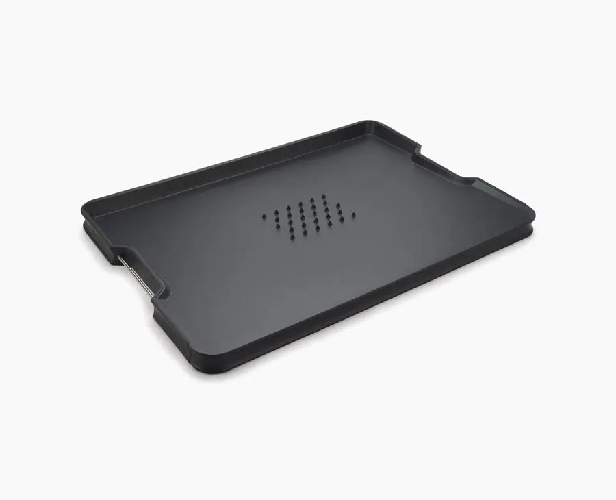 Joseph Joseph Cut&Carve Plus extra-large chopping board in black, spiked carving side up.