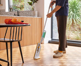 The articulated mop head spraying a fine mist onto a hard floor.