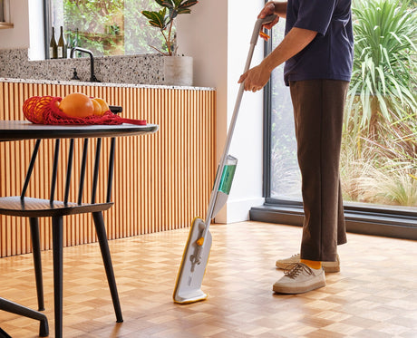 The articulated mop head spraying a fine mist onto a hard floor.