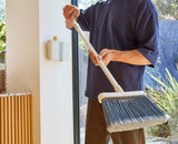 The broom being pushed through the soft rubber flaps of the wall holder.
