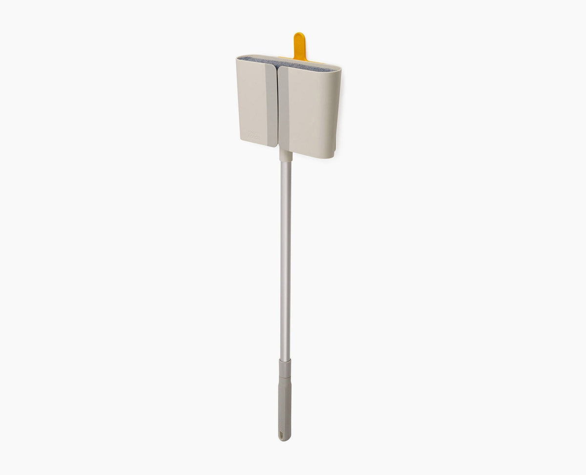 Joseph Joseph CleanTech wall-mounted broom in stone, seated in its Dust-shield holder.
