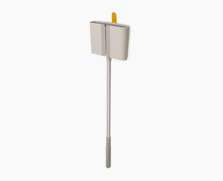 Joseph Joseph CleanTech wall-mounted broom in stone, seated in its Dust-shield holder.