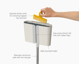 The Dust-shield holder mounted on a wall with the broom stored inside.