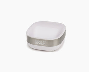 Joseph Joseph Slim compact stainless-steel soap dish in white, holding a bar of soap.