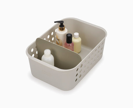 Joseph Joseph EasyStore large bathroom storage basket in ecru, filled with toiletries.