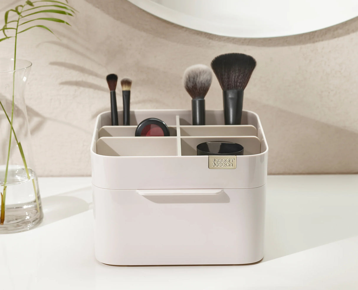 Brushes, mascara and lipsticks sorted into the organiser's compartments.