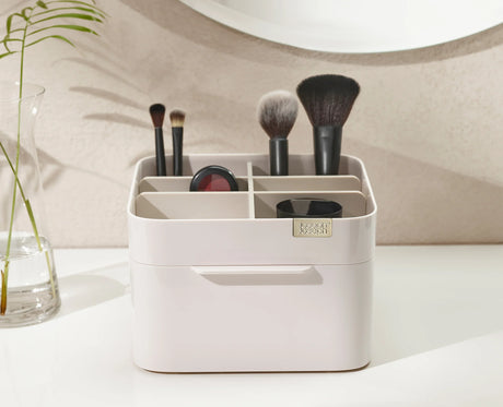 Brushes, mascara and lipsticks sorted into the organiser's compartments.