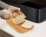 The black bread bin holding loaves and rolls to show its capacity.