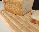 Overall view of the bread bin's black body paired with its bamboo cutting board lid.