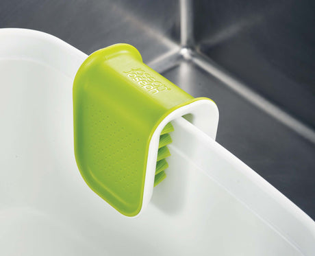 The brush being used to clean a fork under running water.