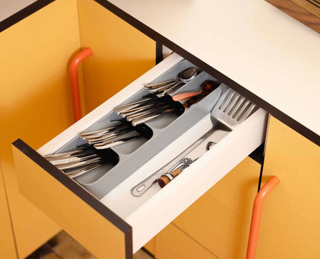 Angled view of the grey organiser showing how the stacked compartments overlap to save drawer space.