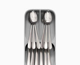The tray sitting inside an open kitchen drawer with cutlery sorted into its tiers.
