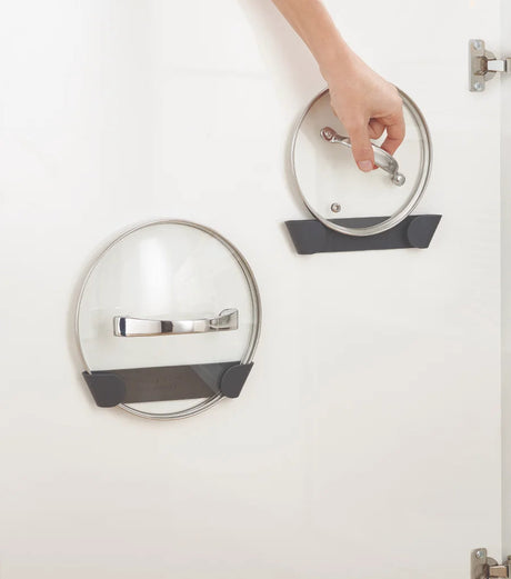 Pan lid holders mounted inside a kitchen cupboard door holding four lids