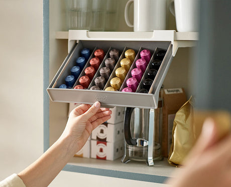 The drawer fixed beneath a cupboard shelf and pulled open to reveal the pods inside.