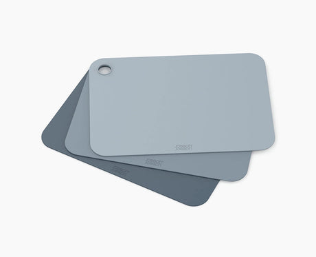 Joseph Joseph Pop set of three flexible chopping mats in blue tones, stacked together.