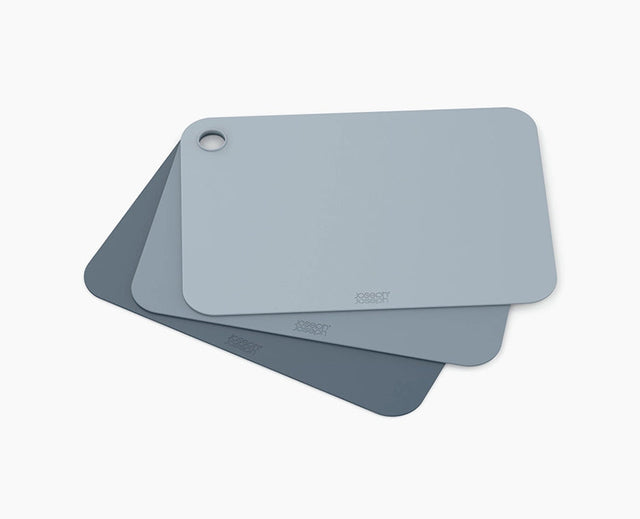Joseph Joseph Pop set of three flexible chopping mats in blue tones, stacked together.