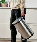 Person carrying a Bon Appetit stainless steel pedal bin by its handle in a kitchen