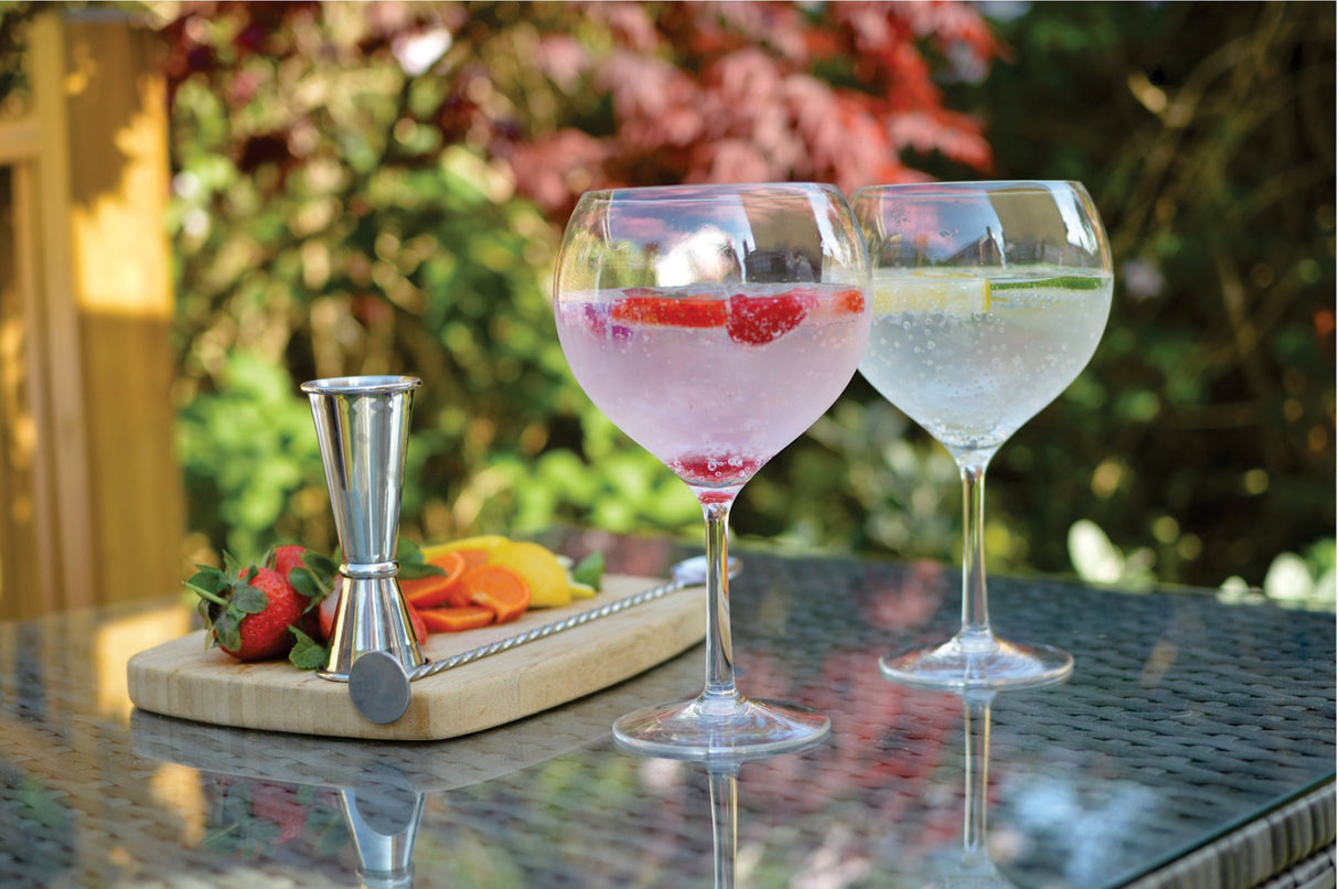Two Bon Appetit 69cL balloon gin and tonic glasses with strawberry and citrus garnish in a garden